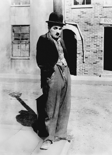 A dog 's life by and with Charlie Chaplin , standing in a street, hands in pockets. Los Angeles